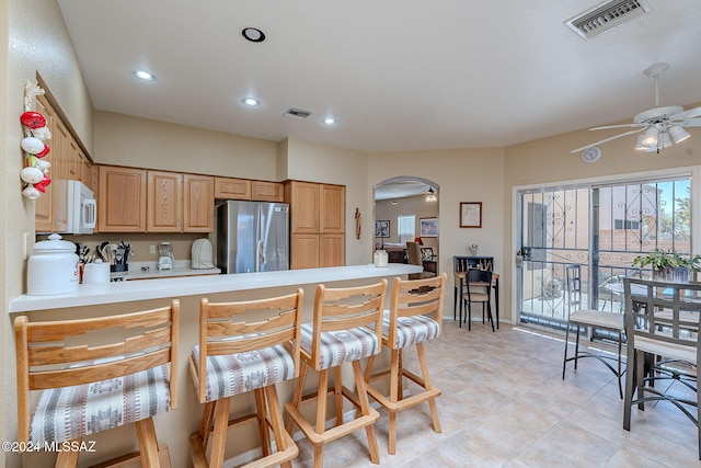 kitchen featuring kitchen peninsula, light brown cabinetry, stainless steel refrigerator, and ceiling fan