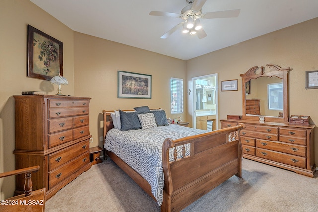 bedroom with multiple windows, light carpet, ensuite bathroom, and ceiling fan