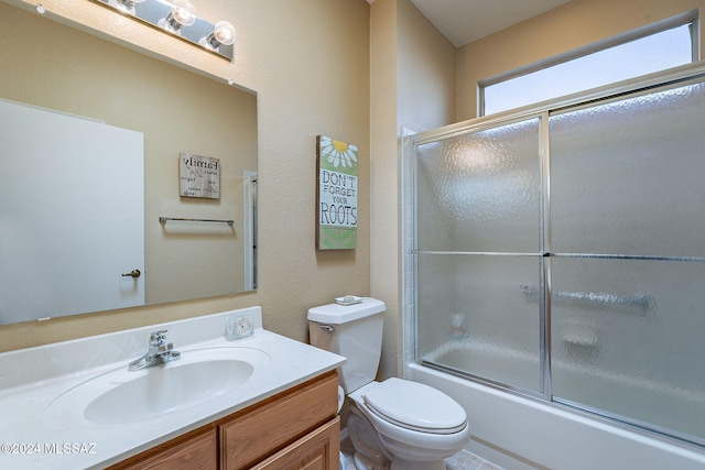 full bathroom with vanity, bath / shower combo with glass door, and toilet