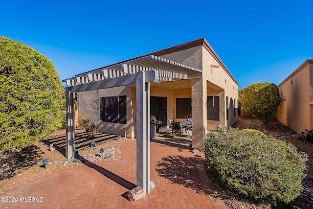 back of property with a pergola and a patio area