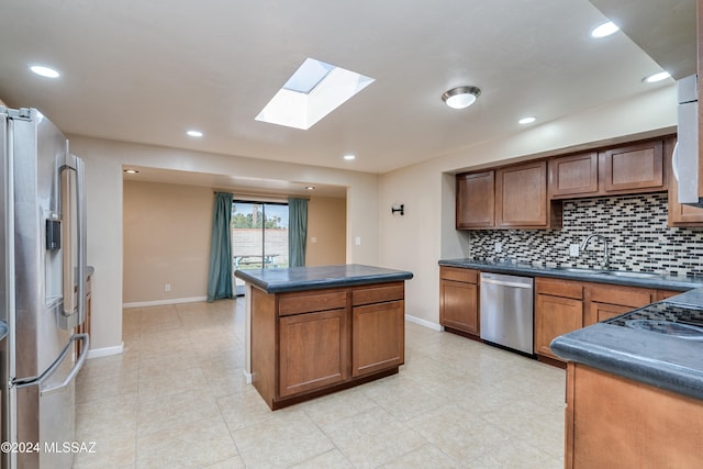 kitchen featuring tasteful backsplash, a skylight, stainless steel appliances, sink, and a center island