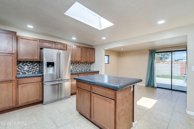 kitchen with stainless steel fridge with ice dispenser, tasteful backsplash, a kitchen island, and light tile patterned flooring