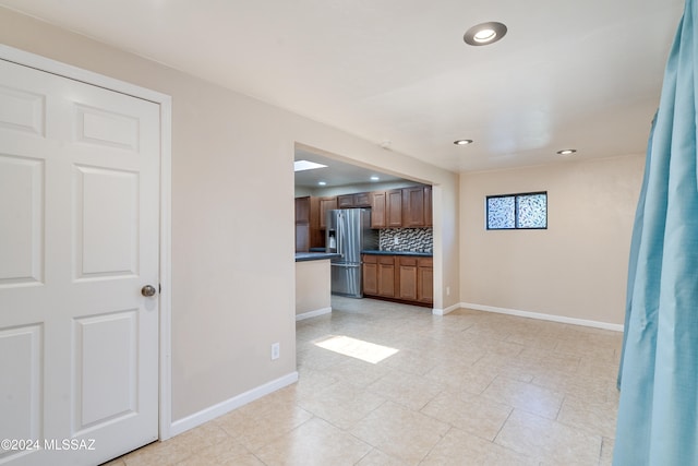 kitchen with stainless steel fridge, backsplash, and light tile patterned flooring