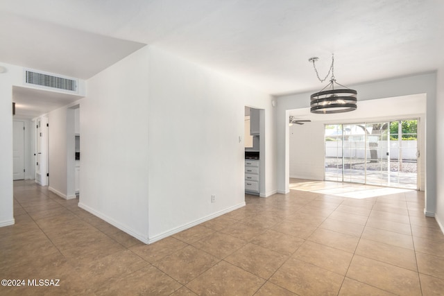 unfurnished room featuring ceiling fan with notable chandelier and light tile patterned floors