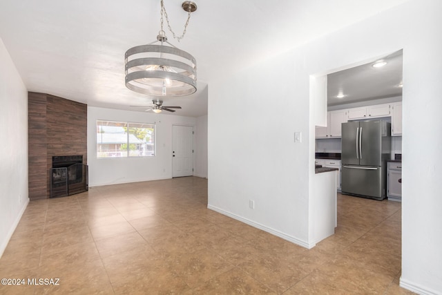 unfurnished living room featuring ceiling fan with notable chandelier and a fireplace