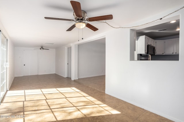 tiled spare room with ceiling fan