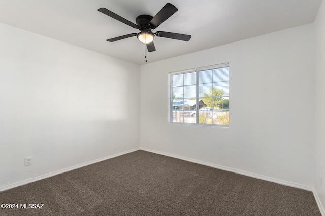 spare room with dark colored carpet and ceiling fan