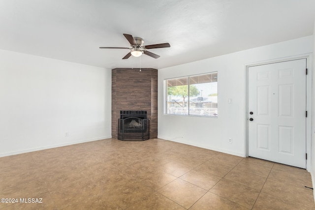 unfurnished living room featuring a large fireplace and ceiling fan