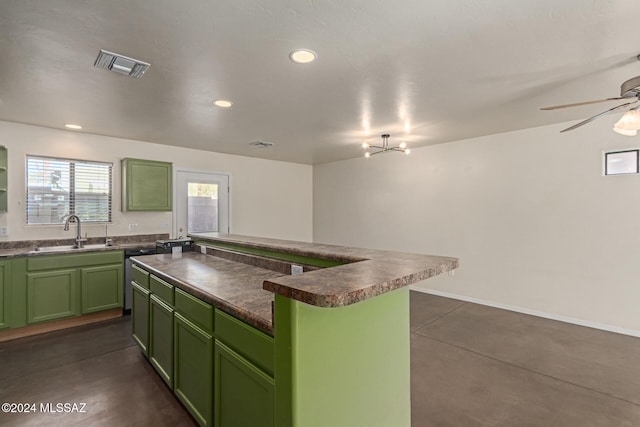 kitchen featuring dishwasher, ceiling fan with notable chandelier, green cabinets, sink, and a kitchen island