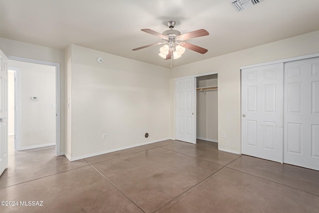 unfurnished bedroom with ceiling fan, concrete flooring, and multiple closets