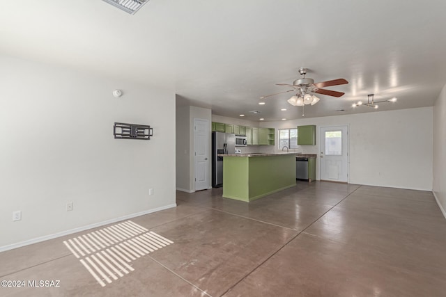 kitchen with ceiling fan, stainless steel appliances, green cabinets, concrete flooring, and a kitchen island