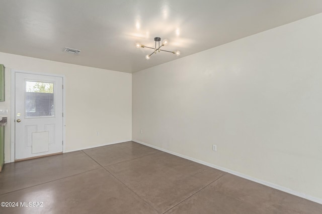 unfurnished room with concrete flooring and a chandelier