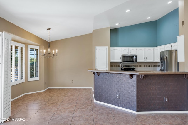 kitchen featuring white cabinets, hanging light fixtures, a breakfast bar area, kitchen peninsula, and stainless steel appliances