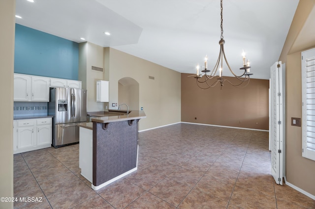 kitchen featuring stainless steel fridge with ice dispenser, backsplash, a chandelier, pendant lighting, and a breakfast bar