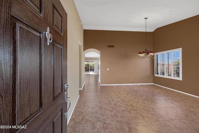 entryway featuring light tile patterned floors, an inviting chandelier, and a high ceiling