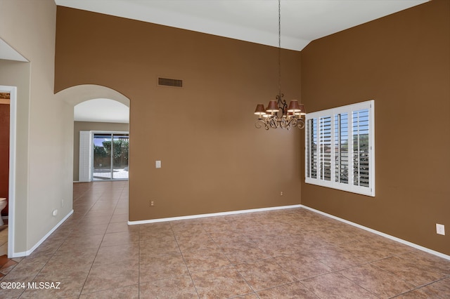 tiled empty room with a chandelier and a high ceiling