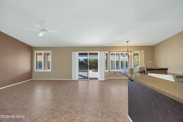 interior space featuring light tile patterned flooring, ceiling fan with notable chandelier, and sink