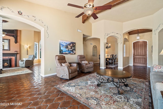 living room with a fireplace, beamed ceiling, and ceiling fan