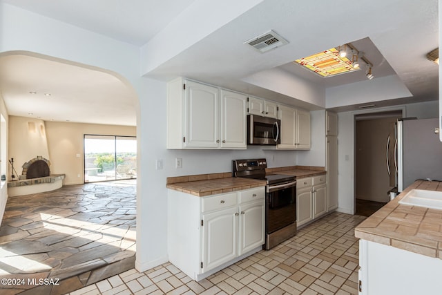 kitchen with tile countertops, white cabinets, and stainless steel appliances