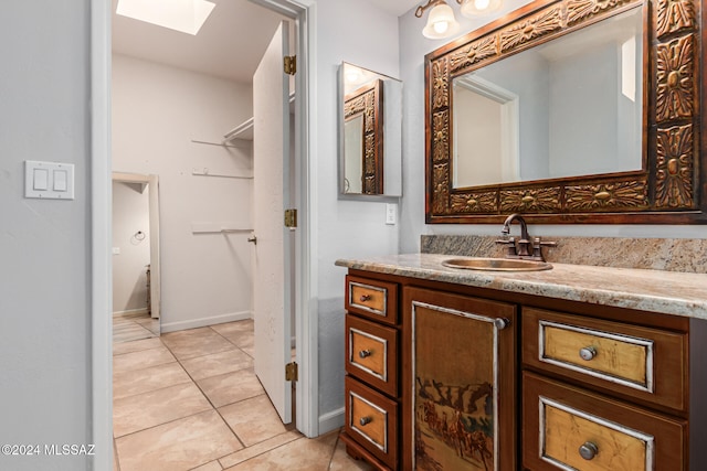 bathroom featuring tile patterned flooring, vanity, and a skylight