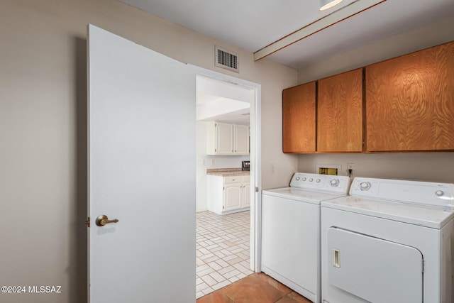 clothes washing area with cabinets and washer and clothes dryer