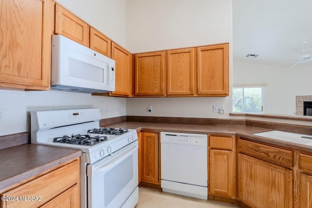 kitchen featuring white appliances, ceiling fan, sink, light tile patterned floors, and a fireplace