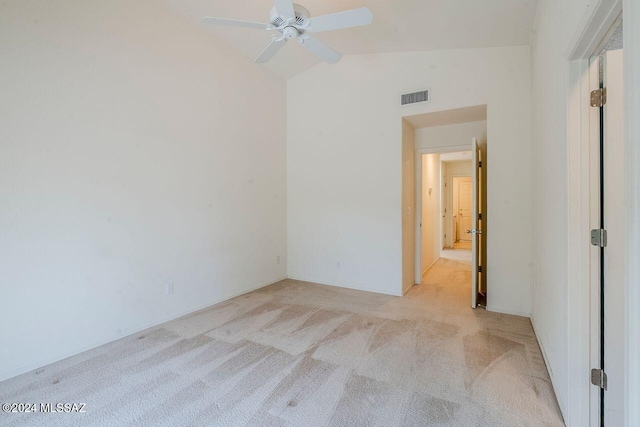 spare room featuring light carpet, vaulted ceiling, and ceiling fan