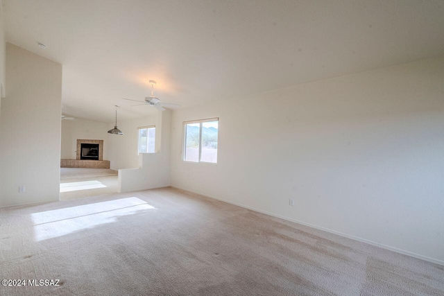 carpeted spare room featuring ceiling fan, lofted ceiling, and a fireplace