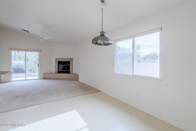 unfurnished living room featuring carpet flooring, ceiling fan, a fireplace, and vaulted ceiling