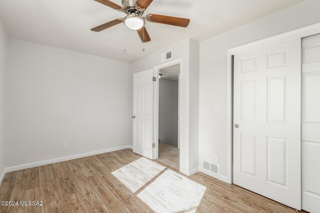 spare room with ceiling fan, beam ceiling, wood-type flooring, and brick wall