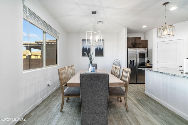 dining area with light hardwood / wood-style floors and a notable chandelier