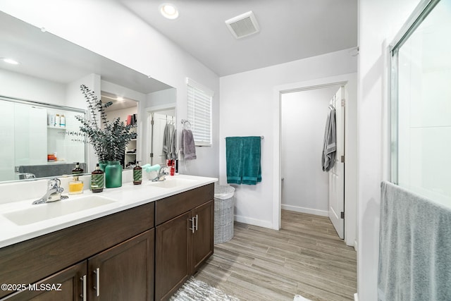 bathroom with walk in shower, vanity, and wood-type flooring