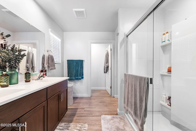 bathroom featuring vanity, wood-type flooring, and a shower with shower door