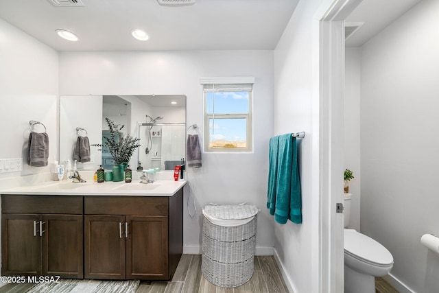 bathroom featuring vanity, hardwood / wood-style flooring, a shower with door, and toilet