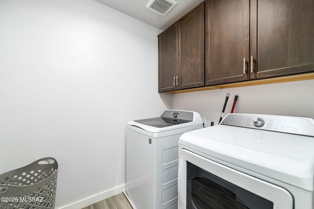 washroom featuring separate washer and dryer, cabinets, and light wood-type flooring