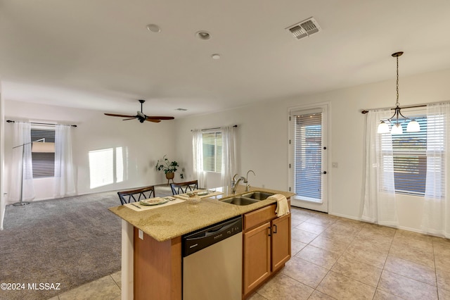 kitchen with plenty of natural light, dishwasher, hanging light fixtures, and a center island with sink