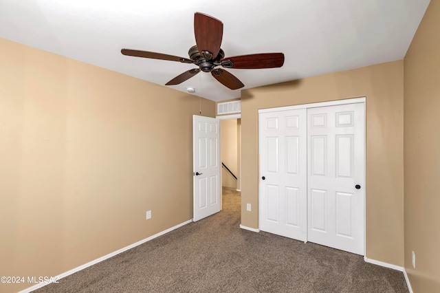 unfurnished bedroom with dark colored carpet, ceiling fan, and a closet