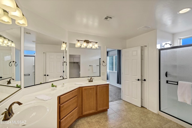 bathroom with a shower with door, vanity, and tile patterned flooring