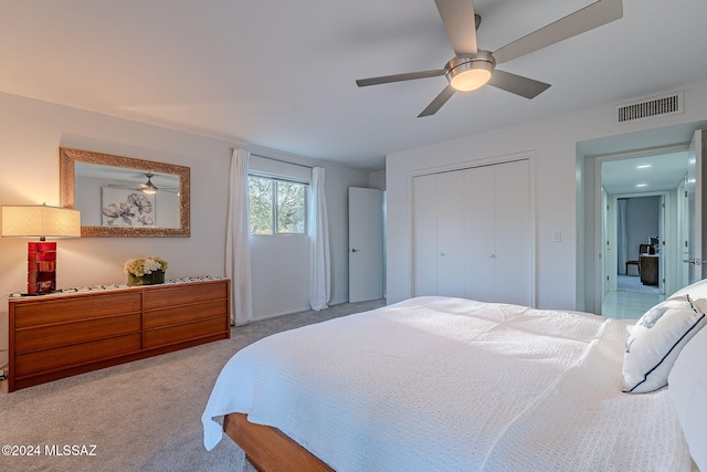 bedroom with ceiling fan, light colored carpet, and a closet