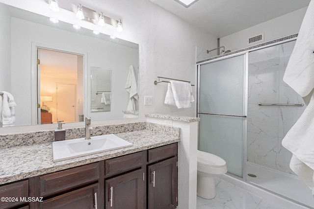 bathroom featuring a shower with door, vanity, and toilet