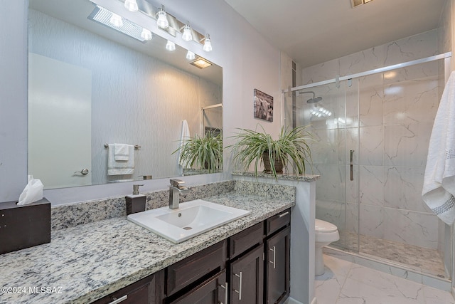 bathroom featuring vanity, a shower with shower door, and toilet