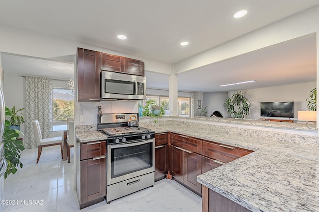 kitchen with light stone countertops, backsplash, a wealth of natural light, and stainless steel appliances