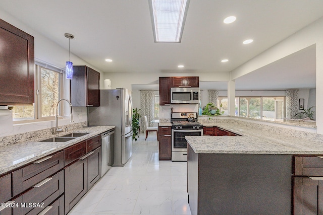 kitchen featuring decorative light fixtures, light stone counters, sink, and appliances with stainless steel finishes