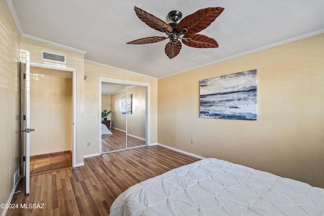 bedroom with ceiling fan, wood-type flooring, crown molding, and a closet