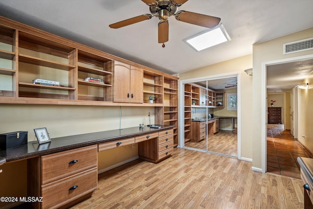 office featuring ceiling fan, light wood-type flooring, built in desk, and sink