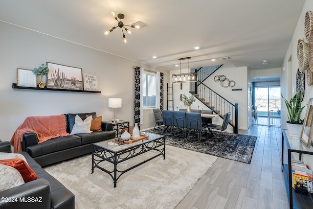 living room featuring a wealth of natural light, an inviting chandelier, and light wood-type flooring