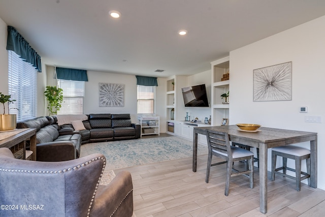 living room featuring built in features and light wood-type flooring