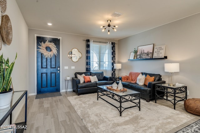 living room with light wood-type flooring and an inviting chandelier