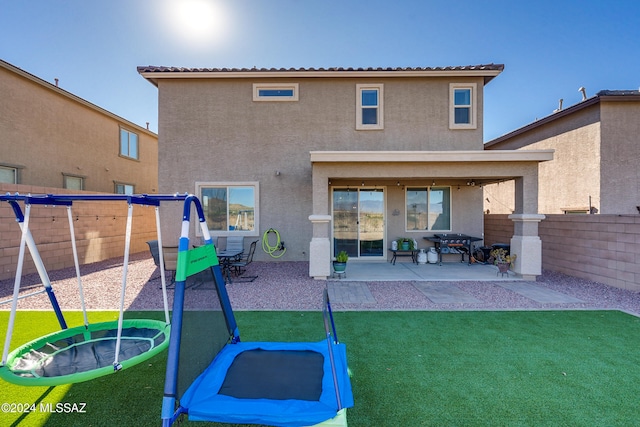 rear view of house featuring a patio area, a playground, and a yard