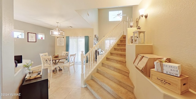 stairs with tile patterned floors, ceiling fan, and a healthy amount of sunlight